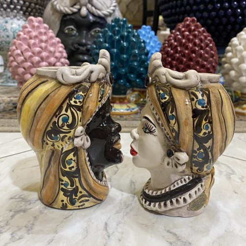 Pair of Caltagirone ceramic heads, with frieze and turban on a mustard-colored background, approx. h 13 cm. RP mod -  2