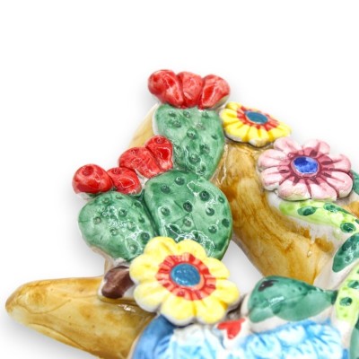 Trinacria in ceramica Caltagirone, con applicazioni di Pale ficodindia e fiori, h 36 cm ca. - 